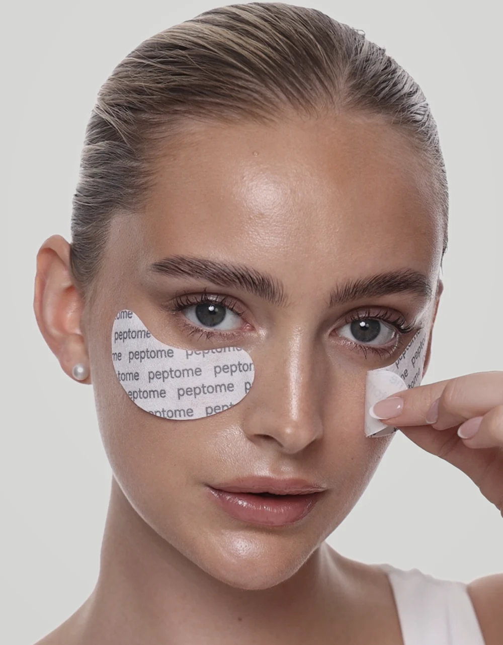 Peeling a Peptome under-eye patch from the backing